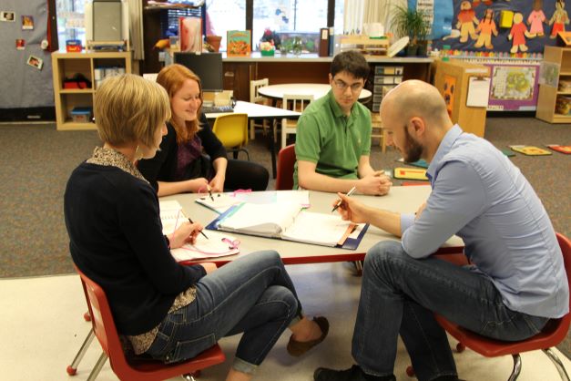 Group of adults gathered round a table in a daycare setting.