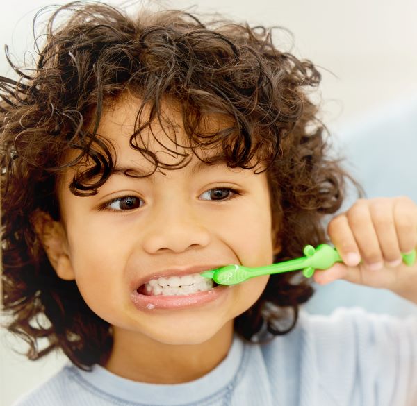 Niño felizmente cepillándose los dientes