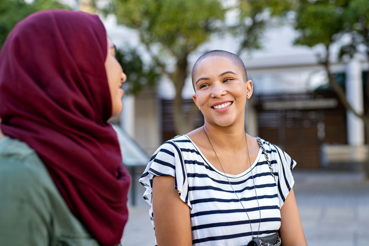 Two women talking while sitting outdoors.