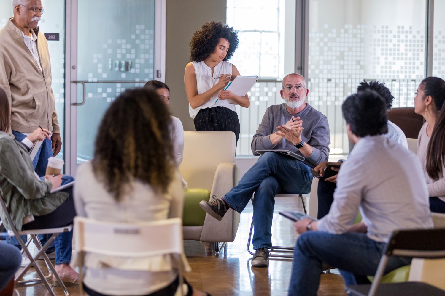 Several people gathered for a meeting with some taking notes.