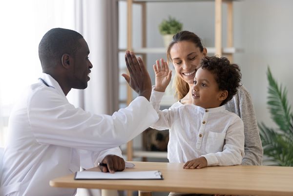 Health professional doing a high-five to a child accompanied by his mother.