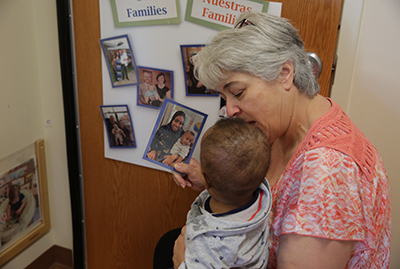 A teacher showing a young boy a photo of him with his mother.