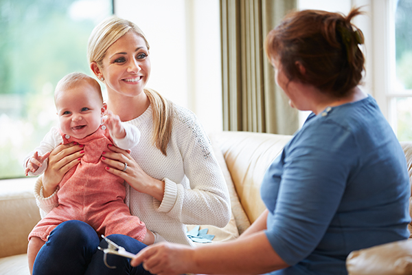 Woman talking with a mother and her baby.