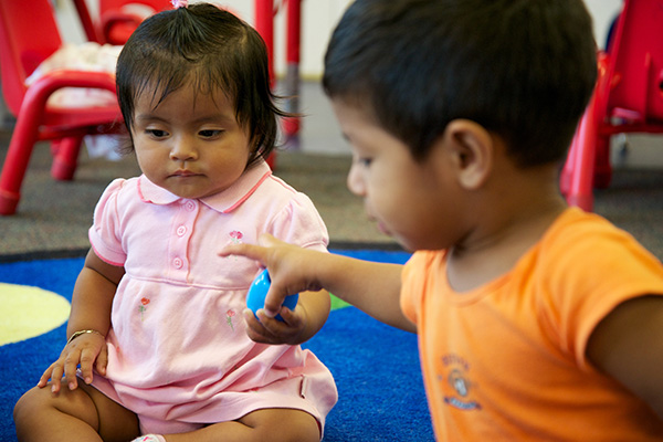 Toddlers sharing a toy.