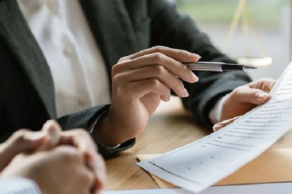 Individual pointing to a document with a pen.