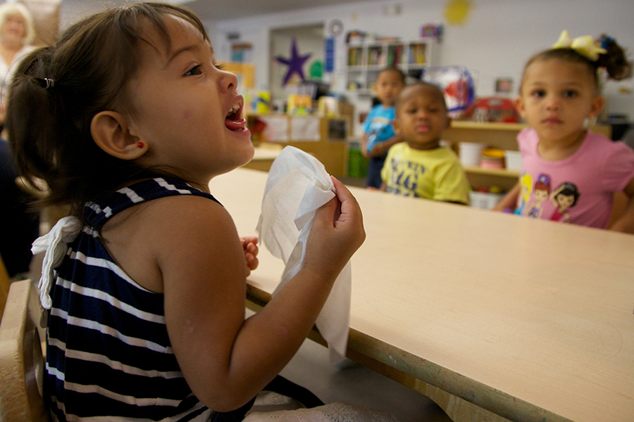 Niña usando un pañuelo de papel para sonarse la nariz.