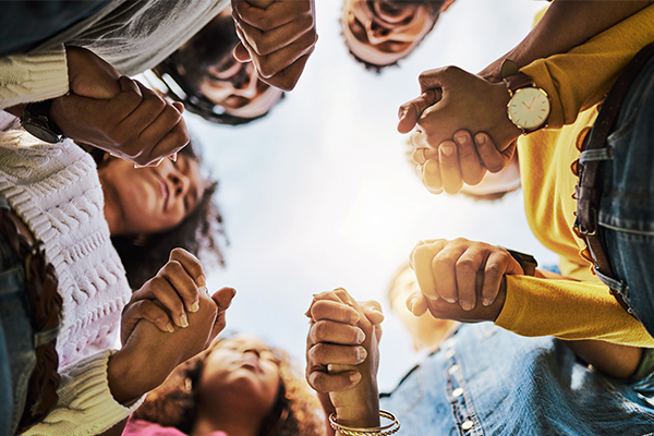 Group of adults holding hands while forming a circle.