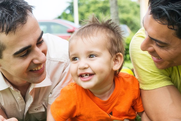 Parents holding a child and smiling to him.