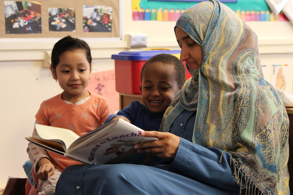 Maestra leyendo un libro a dos niños