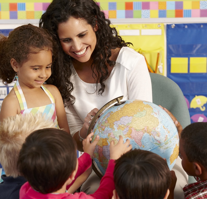 Children looking into a world globe with the teacher.