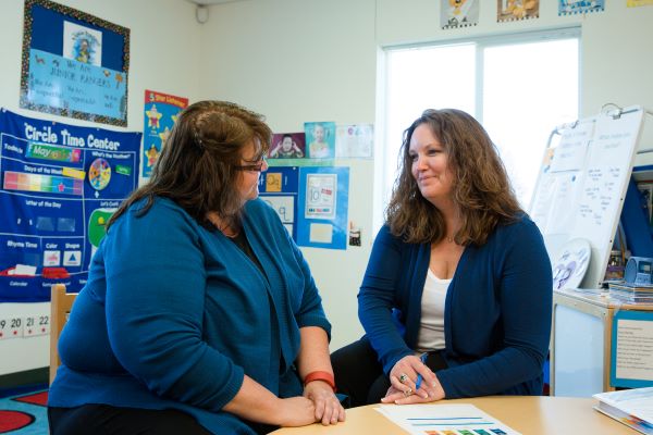 Manager talking with a teacher in a classroom.