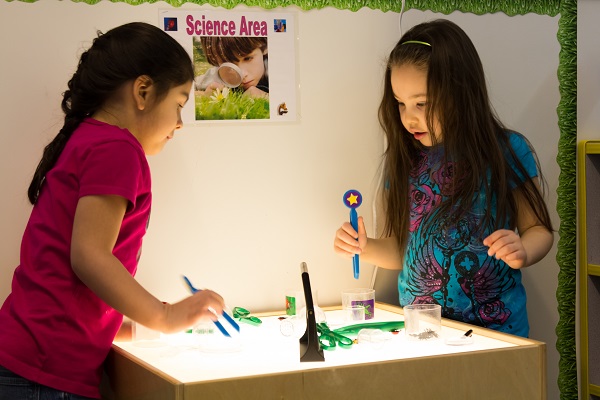 Two preschool girls playing in the science area.