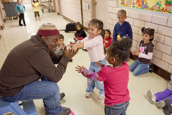 Teacher playing with children in a hallway.