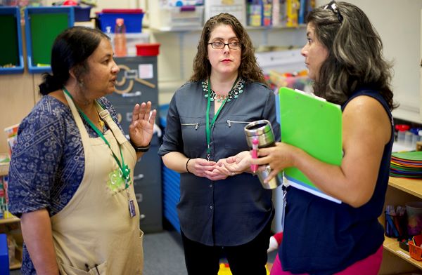 Three women standing having a conversation.