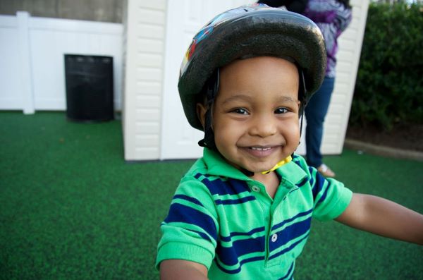 A young boy riding his bicyle wearing a helmet.