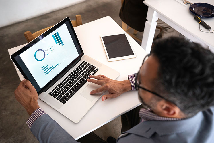 Man looking to a graph in his laptop.