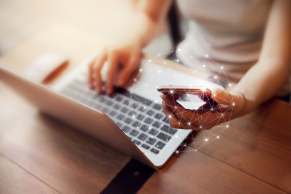 Mujer trabajando con su computadora portátil y su teléfono celular