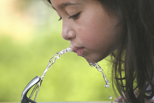 Little girl drinking water from a fountain.