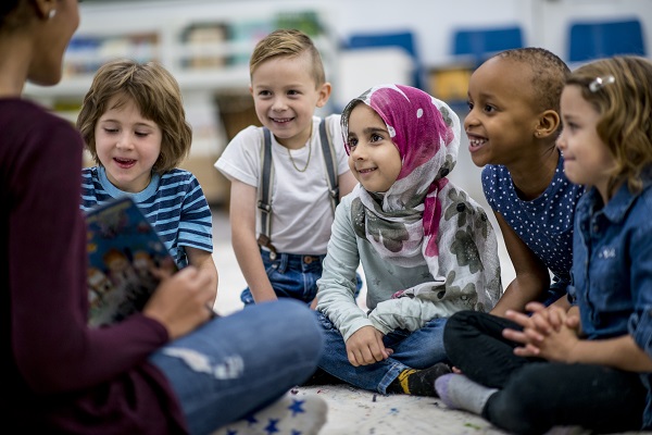 Children of various ethnicities listening carefully to their teacher.