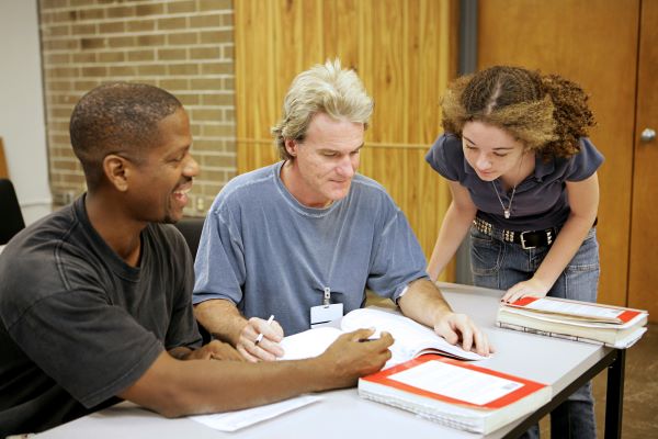 Three adults working together at a desk.