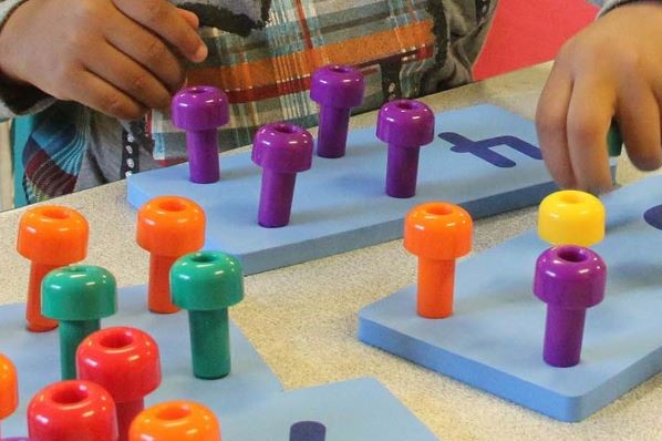 Niño colocando clavijas en un tablero de matemáticas.