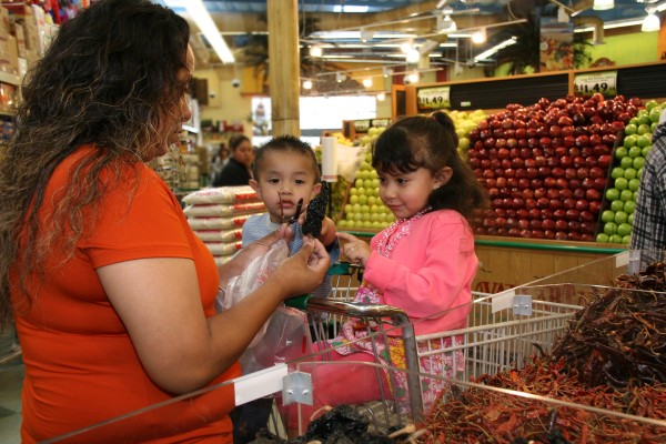 Mother selecting vegetables with her children at a produce store.