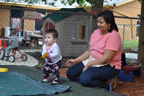 Caregiver taking care of a toodler outdoors.