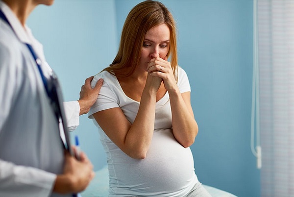 Physician talking with a worried pregnant woman in a clinic's office.