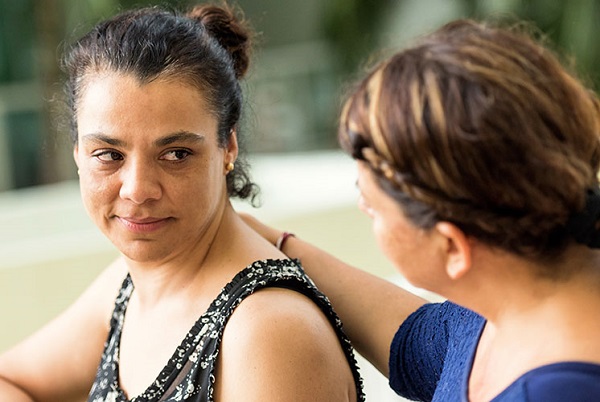 Woman comforting another woman with a hand in her back.