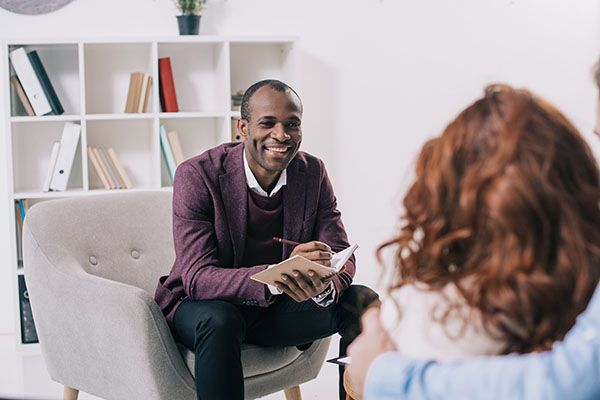 Consultant smiling and talking with a woman in his office.