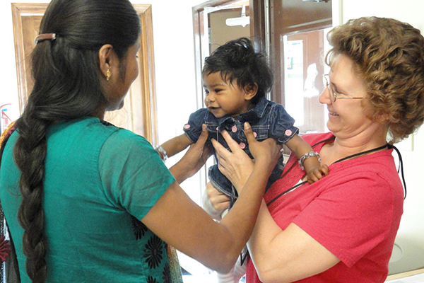 Health professional raising a child from a woman hands.