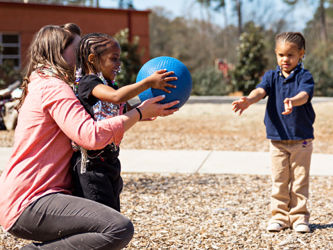 two children and an adult playing with a ball