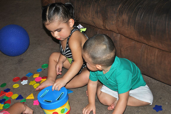 Two toddlers playing with a puzzle game