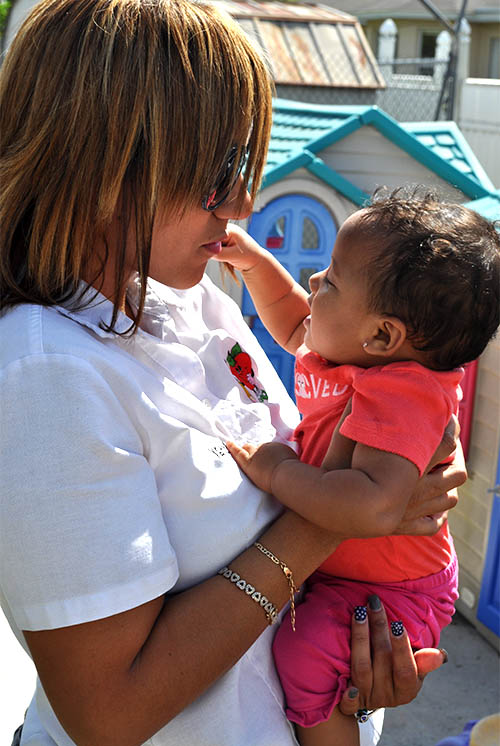 A woman holds a baby who is grasping her hair