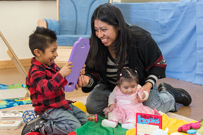 Woman playing with a toddler and baby