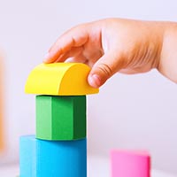 a child's hand is stacking colorful blocks