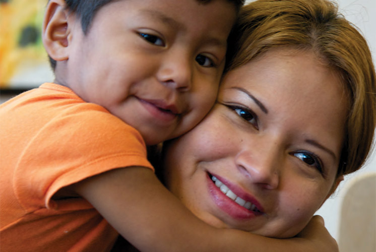 A smiling boy hugging his mom