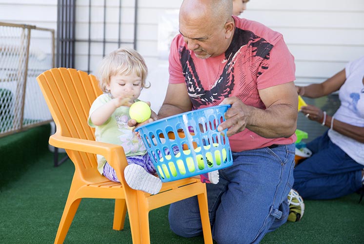 A man helps a child get a ball out of a bucket