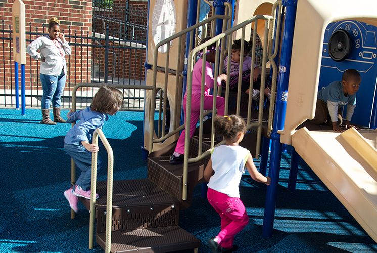 caregiver watching children play on outdoor equipment