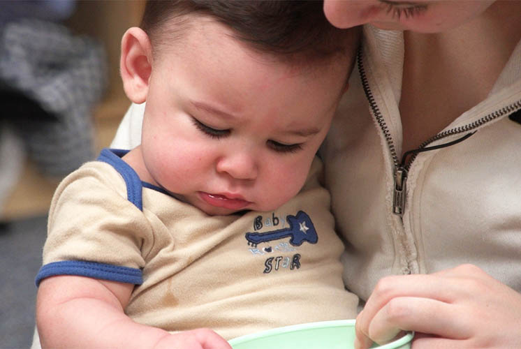 caretaker holding toddler with toy