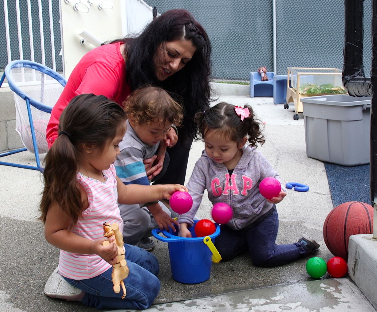 Niños sacando pelotas de un balde.