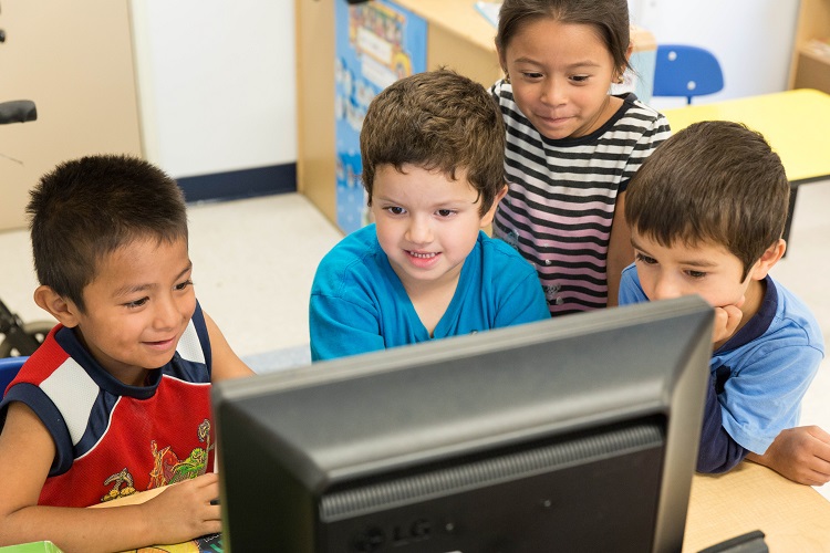 niños mirando a un monitor de computadora