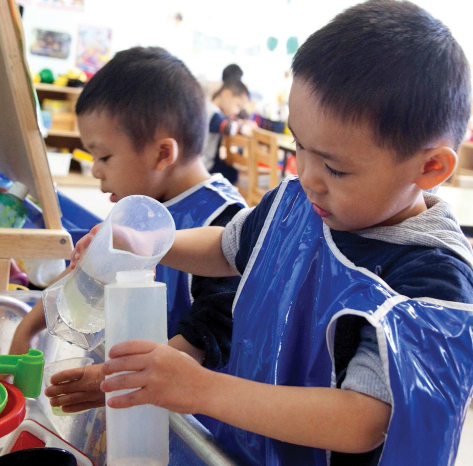 Dos niños vierten agua entre vasos de plástico