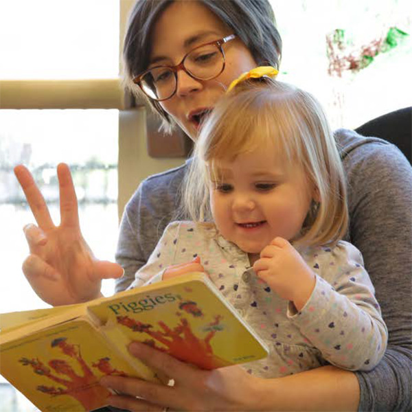 Teacher reading a book to a toddler girl