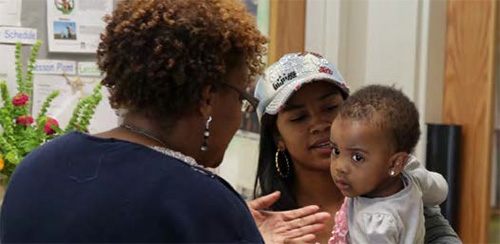 Una maestra habla con una madre y un niño pequeño