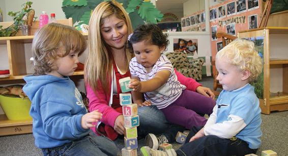 woman and three children playing with blocks