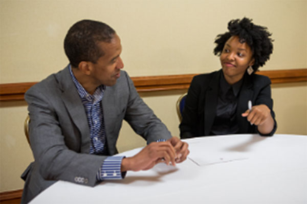 A man and a woman in business attire talking at a table