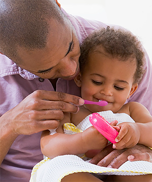 Father brushing his daughter's teeth