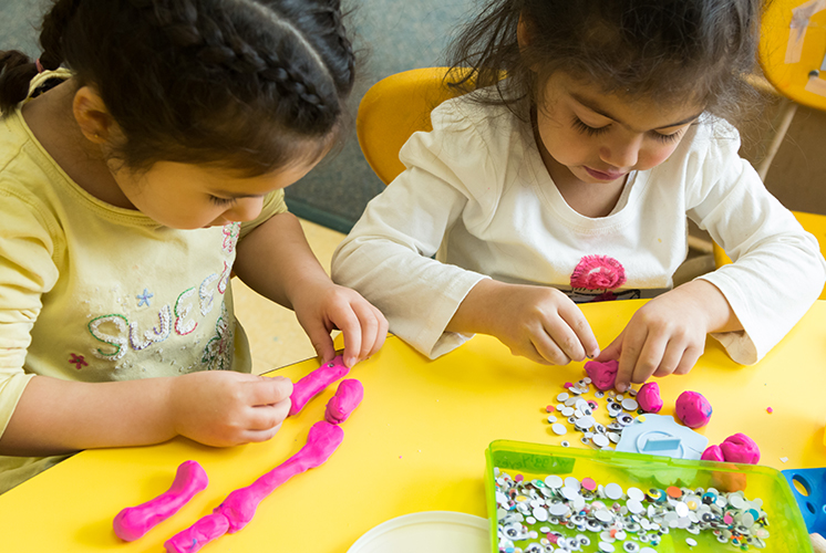 two girls play with clay