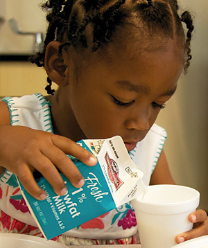 niño vertiendo leche en la taza